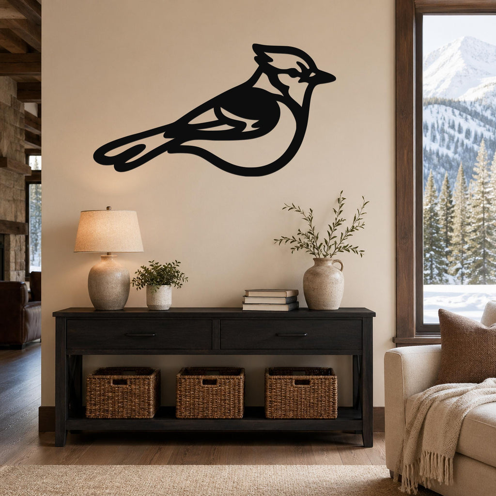 Black metal blue jay wall art silhouette with internal cutout details, mounted on a beige wall above a dark wood console table in a living room.