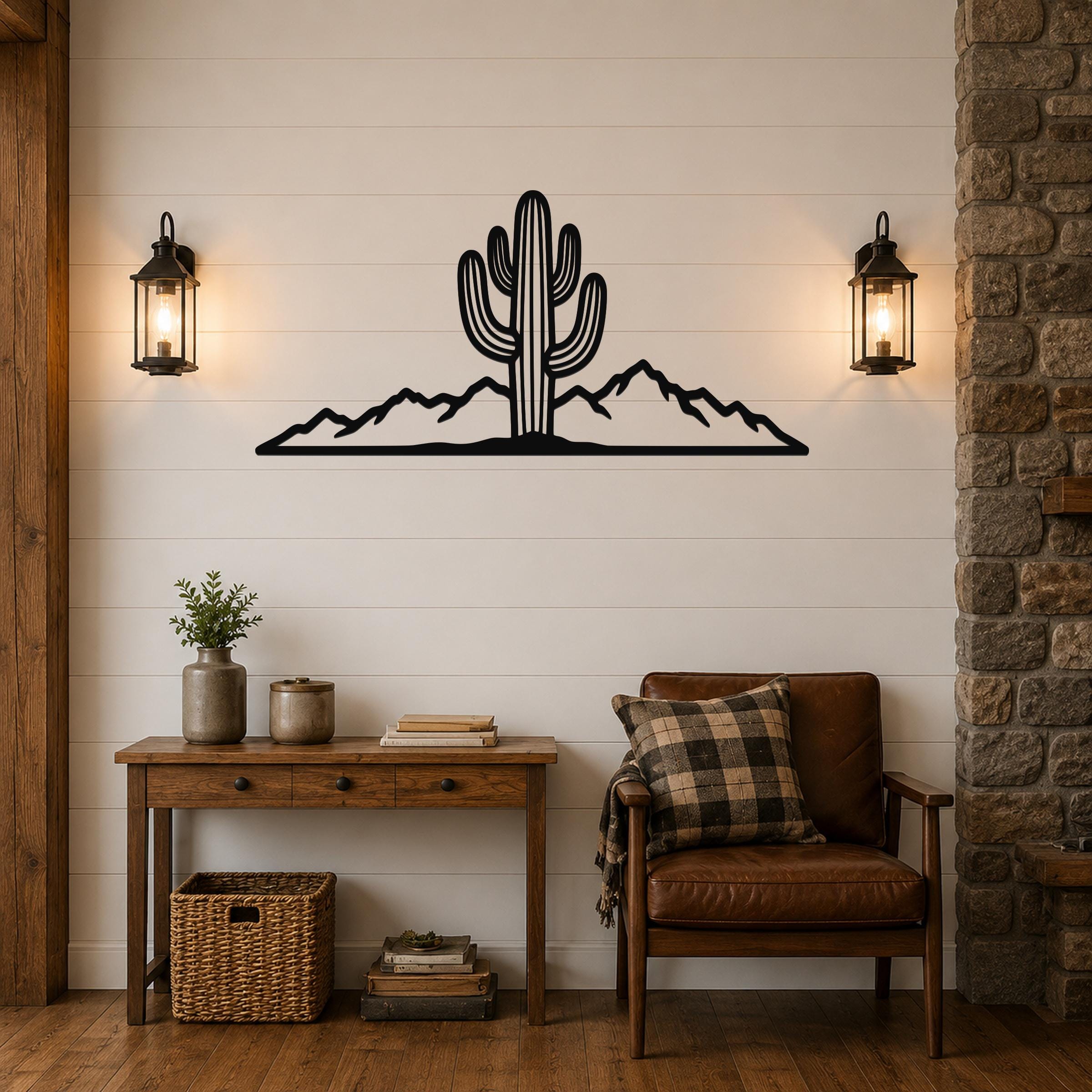 Black metal wall art silhouette of a saguaro cactus and mountain range, mounted on a shiplap wall above a wooden console table in a living room.