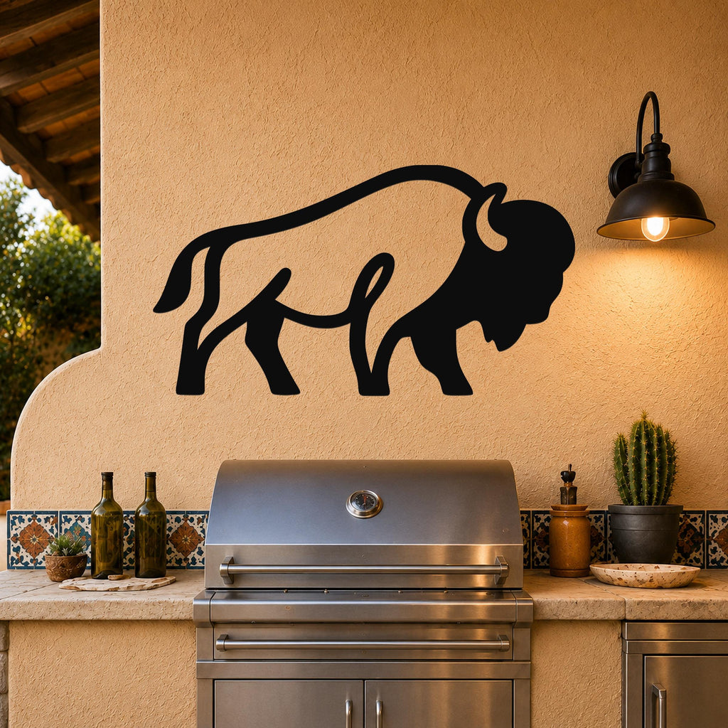 Black metal bison silhouette wall art mounted on a stucco wall above a stainless steel grill in an outdoor kitchen.