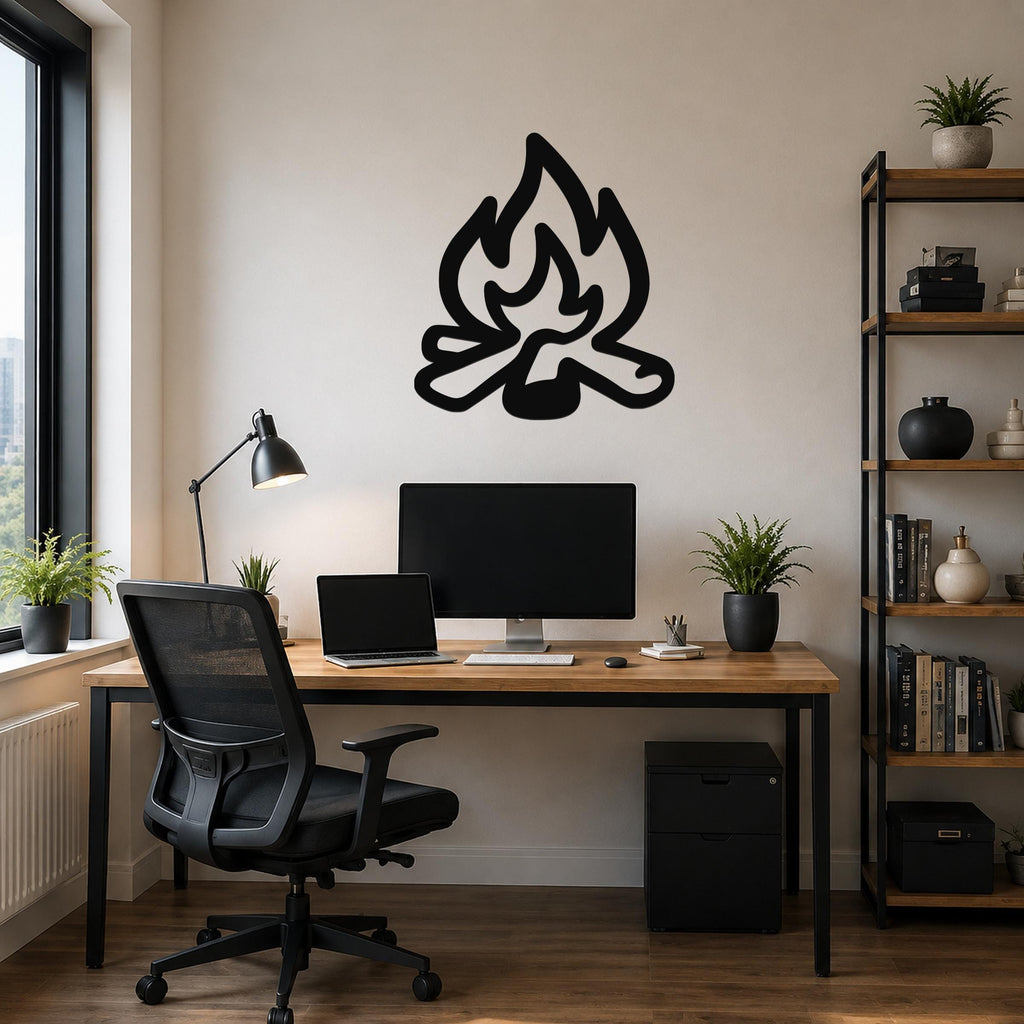 Black metal campfire wall art with flame and log silhouette, mounted above a wooden desk in a home office.