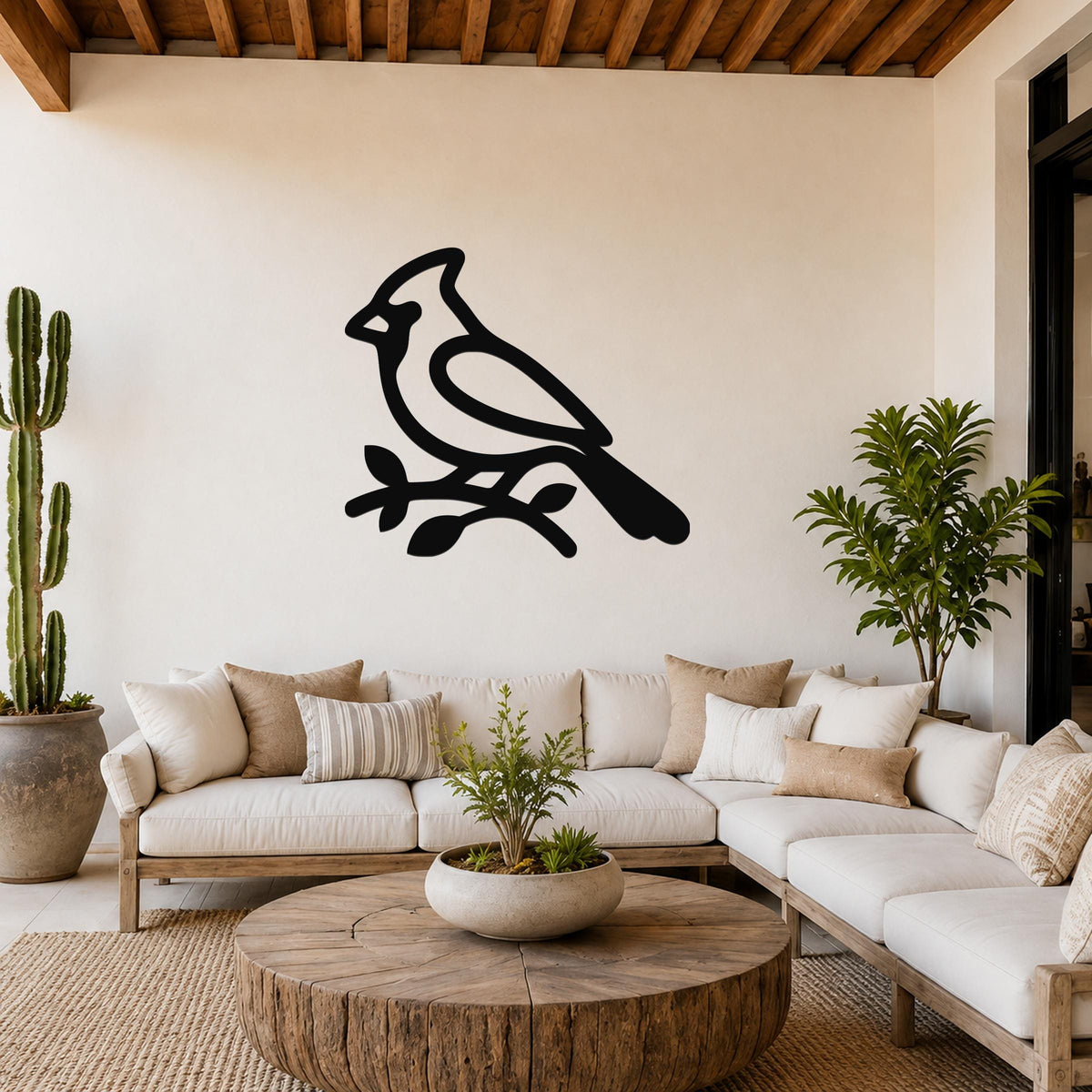 Black metal cardinal wall art silhouette perched on a branch, mounted above a white sofa in a living room.