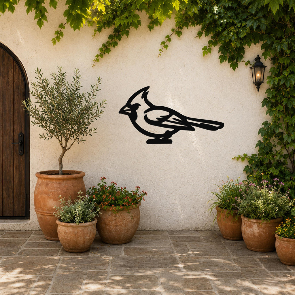 Black metal cardinal wall art silhouette mounted on a stucco outdoor wall above potted plants and a wooden door.