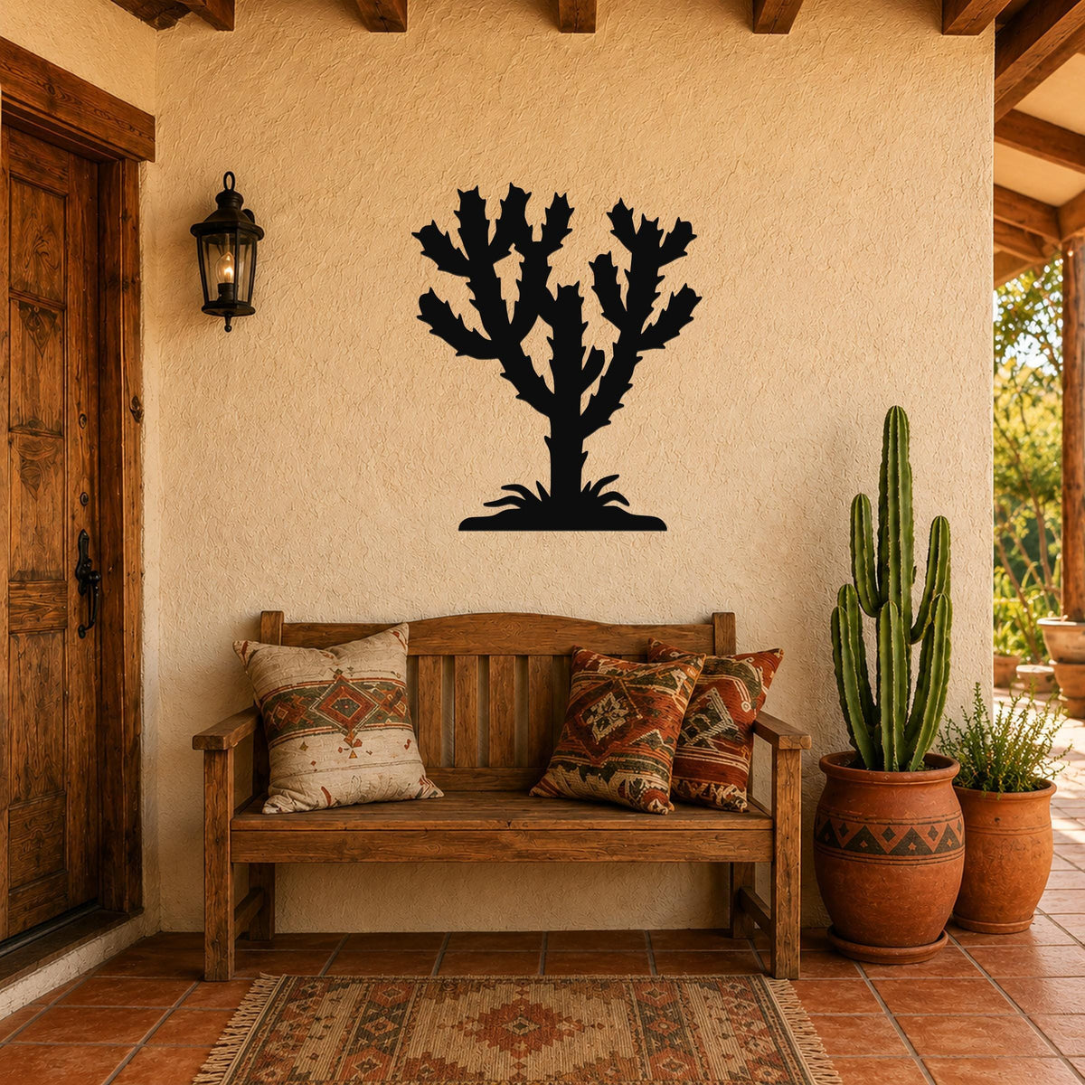 Black metal Cholla cactus wall art silhouette mounted on a stucco wall above a wooden bench in a Southwestern-style entryway.