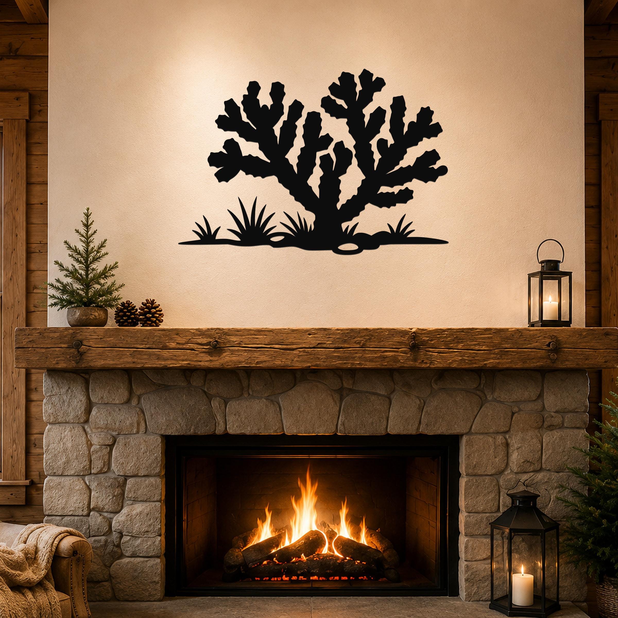 Black metal Cholla cactus wall art with branching silhouette and ground-level spiky plants, mounted above a stone fireplace in a rustic living room.