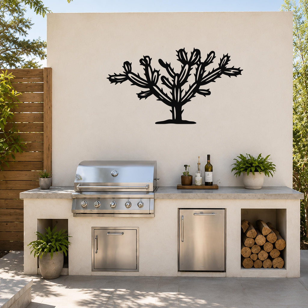 Black metal Cholla cactus wall art silhouette mounted on an outdoor kitchen wall above a stainless steel grill and counter.
