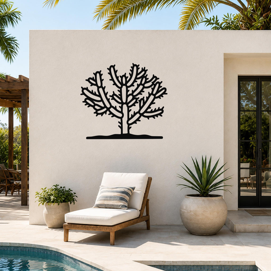 Black metal Cholla cactus wall art with branching silhouette, mounted on an outdoor patio wall above a lounge chair.