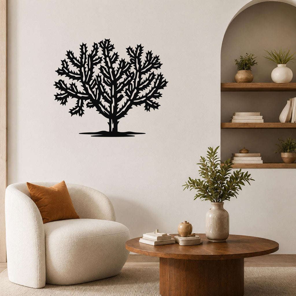 Black metal Cholla cactus wall art with intricate branching cutouts, mounted on a living room wall above a round wooden coffee table.
