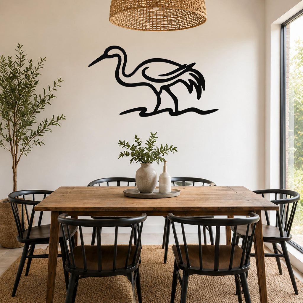 Black metal crane wall art with a minimalist silhouette design, mounted on a white wall above a wooden dining table in a bright, modern dining room.
