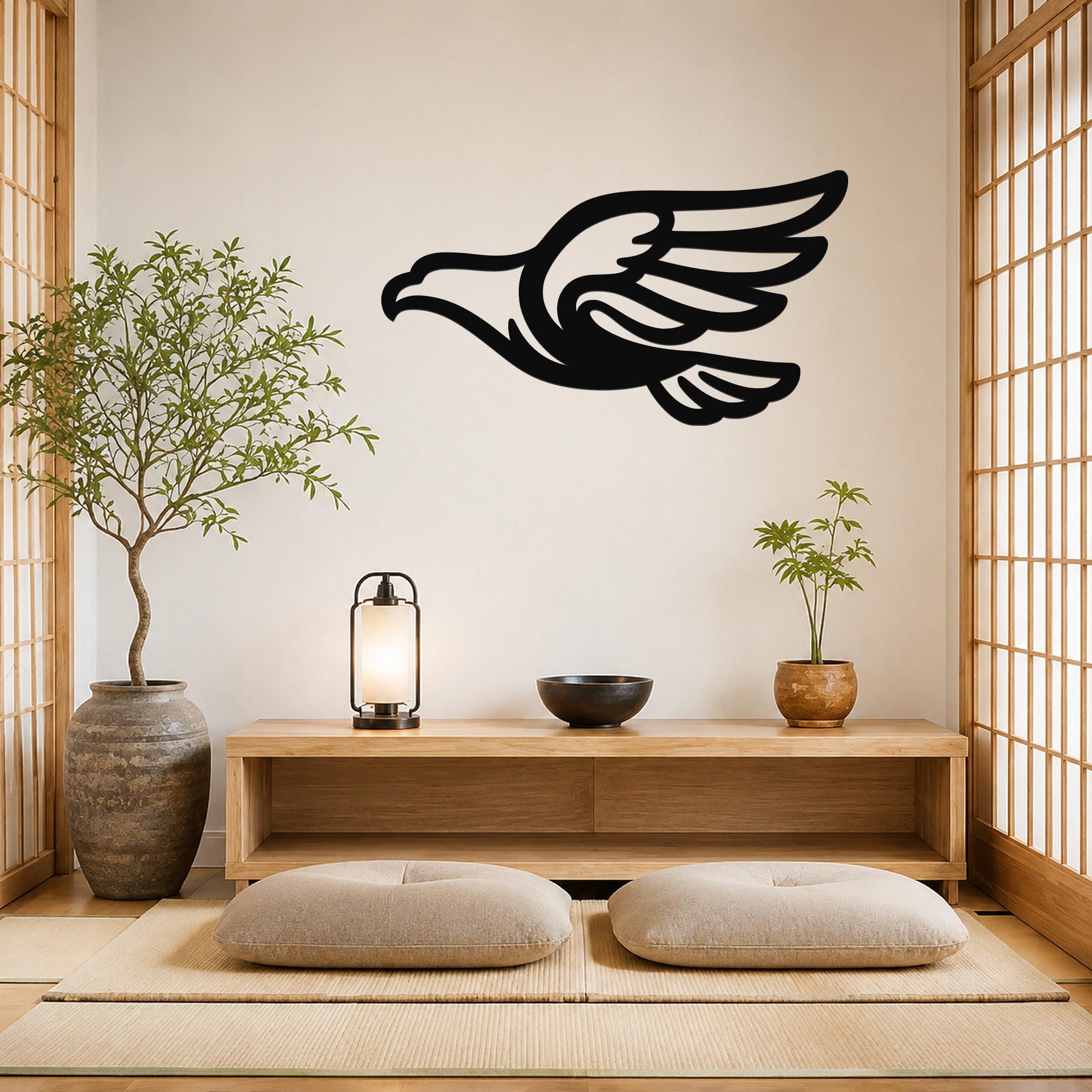 Black metal eagle wall art with a bold silhouette and extended wings, mounted on a light-colored wall above a wooden console in a minimalist room.