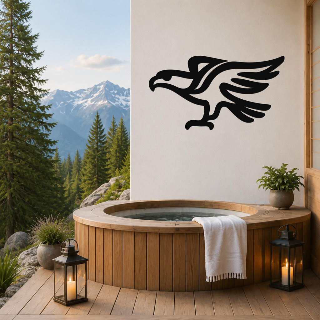 Black metal eagle wall art with a bold silhouette design, mounted on a white wall above a wooden hot tub on a mountain-view deck.