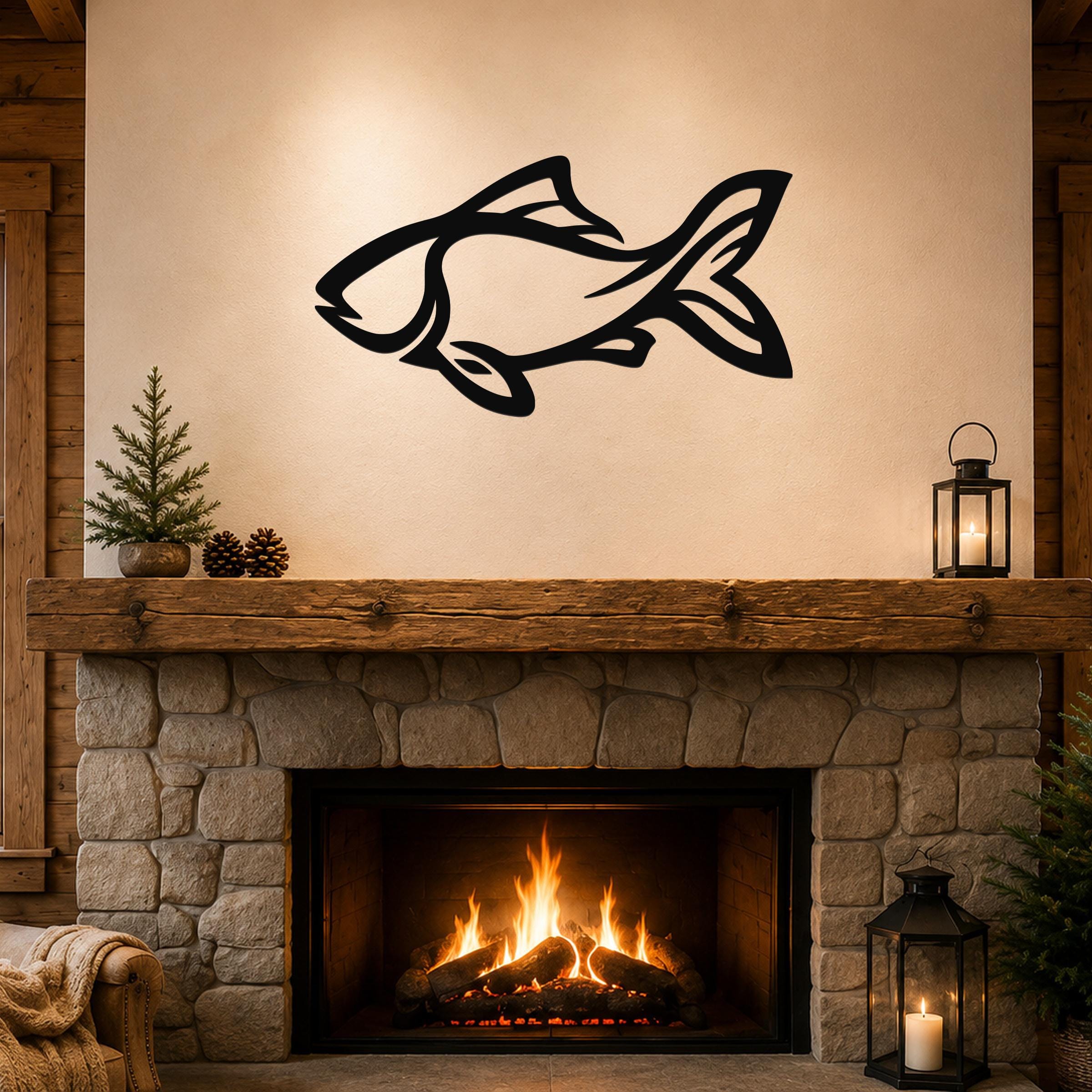 Black metal fish wall art with internal cutout details, mounted above a stone fireplace in a rustic living room.