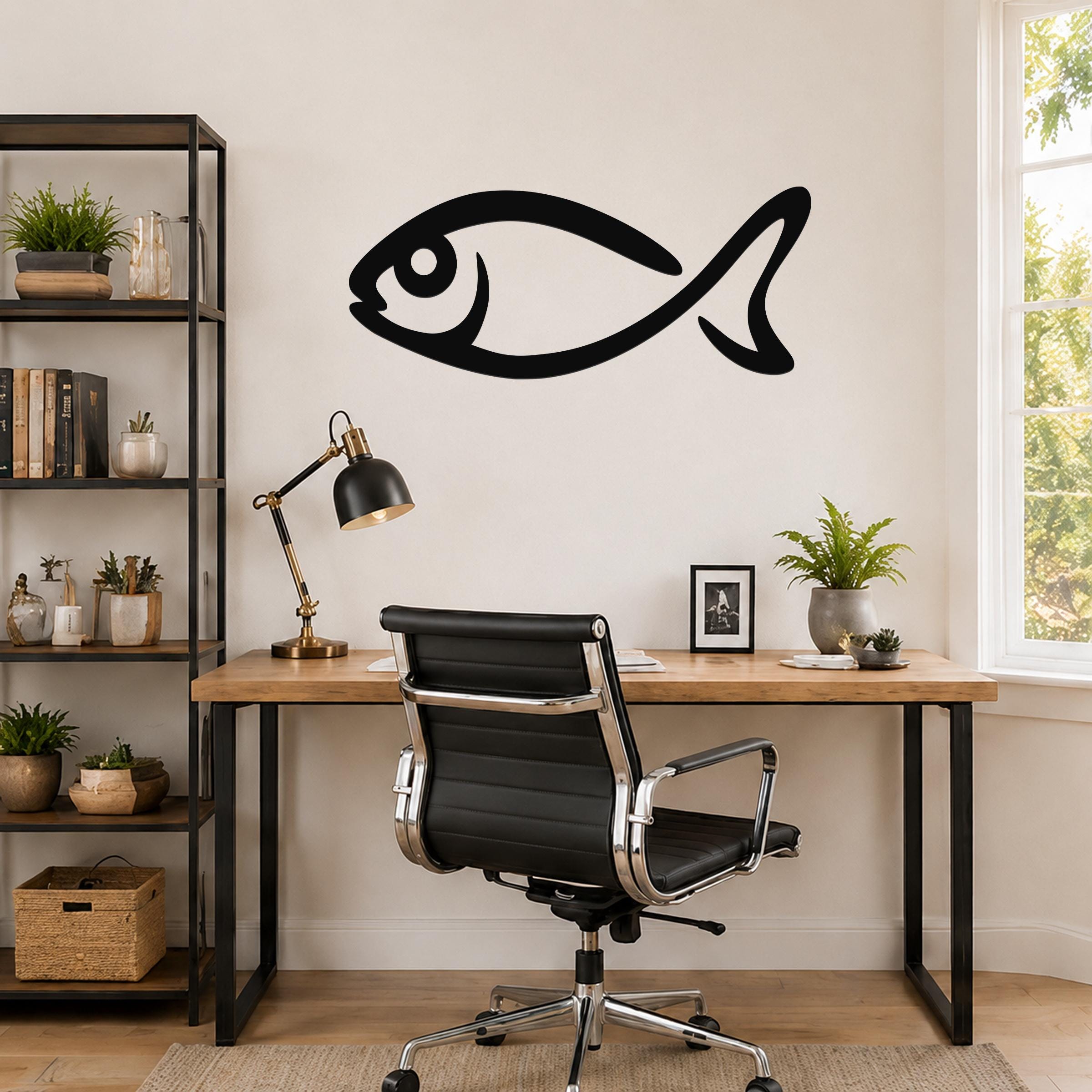 Black metal fish wall art with a bold silhouette design, mounted on a wall above a wooden desk in a home office.