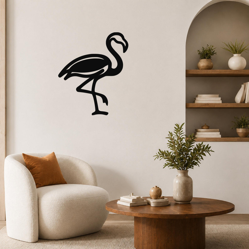 Black metal flamingo wall art silhouette mounted on a living room wall above a white armchair.