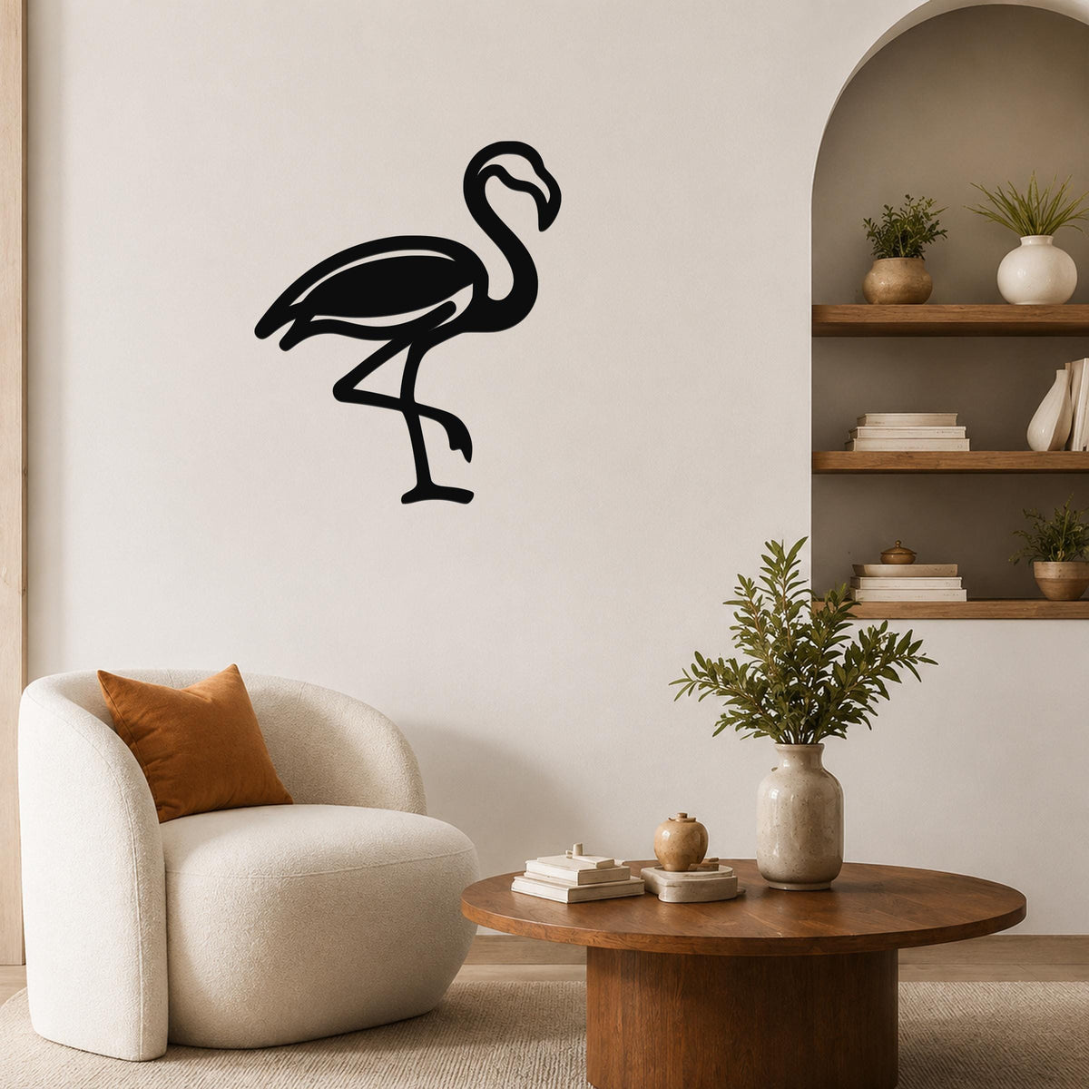 Black metal flamingo wall art silhouette mounted on a living room wall above a white armchair.