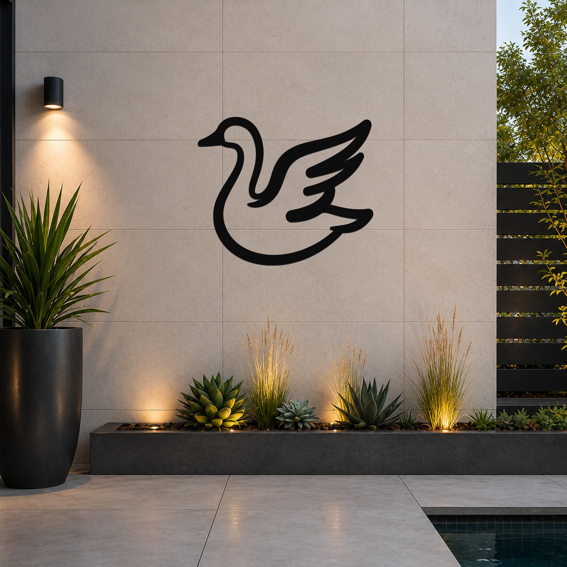 Black metal goose wall art silhouette with wing cutouts, mounted on a tiled outdoor wall above a planter with succulents and uplighting.