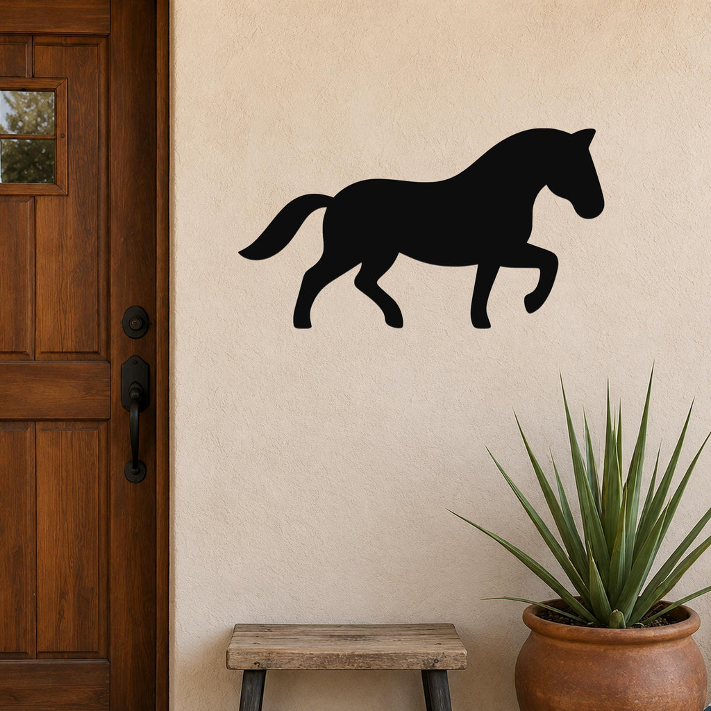 Black metal horse silhouette wall art mounted on a beige stucco wall beside a wooden door, with a potted plant and small bench below.