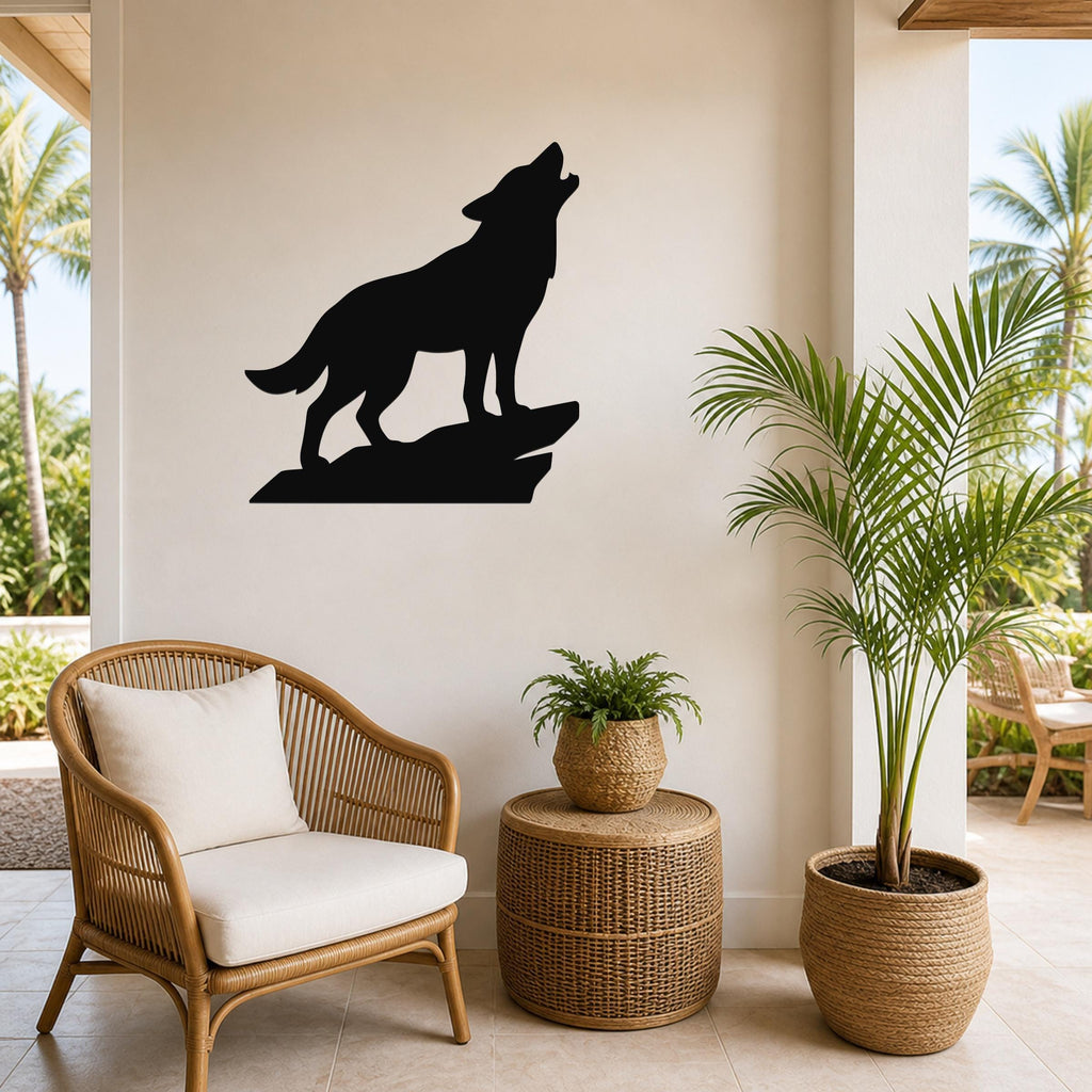Black metal coyote wall art silhouette howling on a rock, mounted on a light-colored wall above a wicker chair in a patio setting.