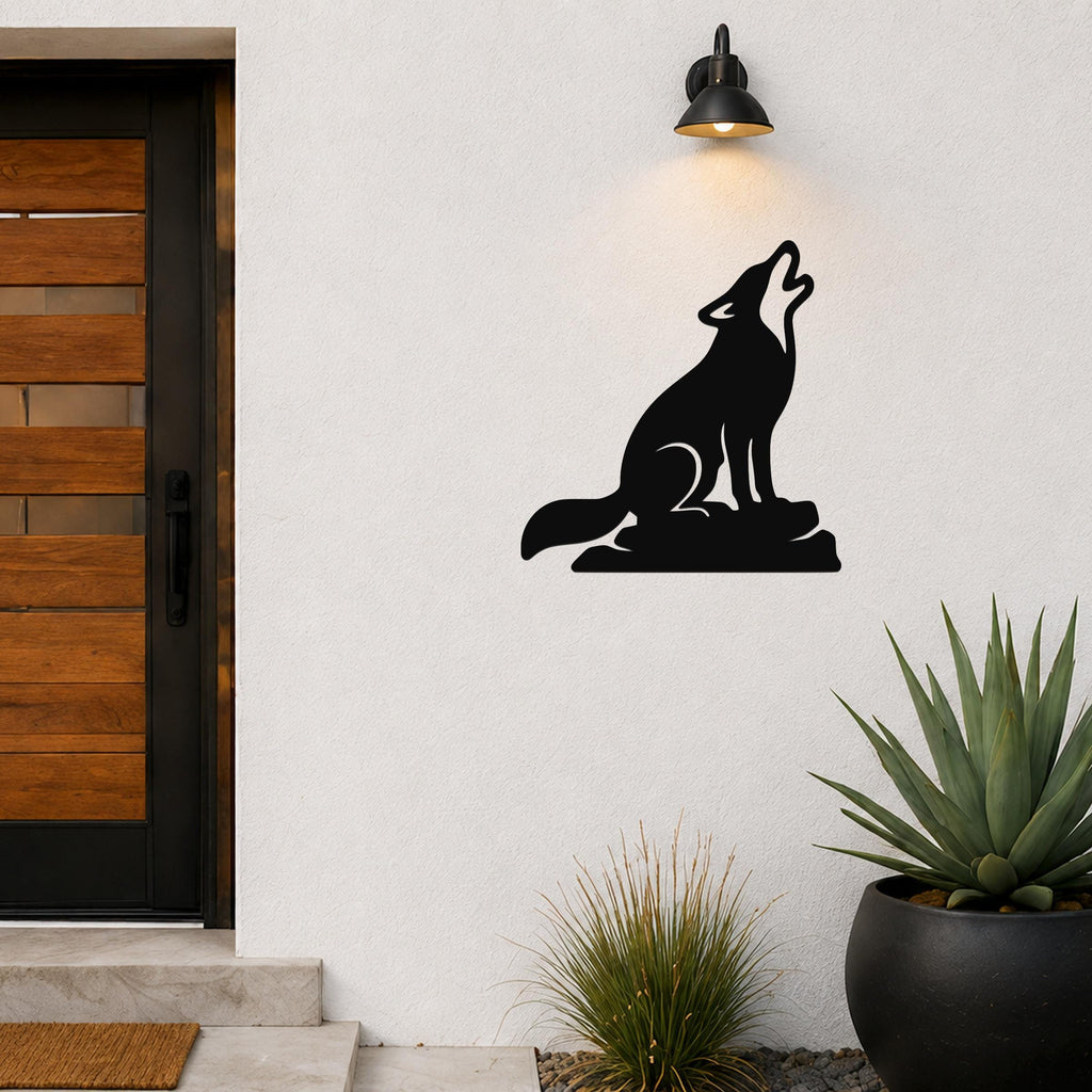 Black metal coyote wall art in a howling silhouette, mounted on a white exterior wall above a potted succulent and near a front door.
