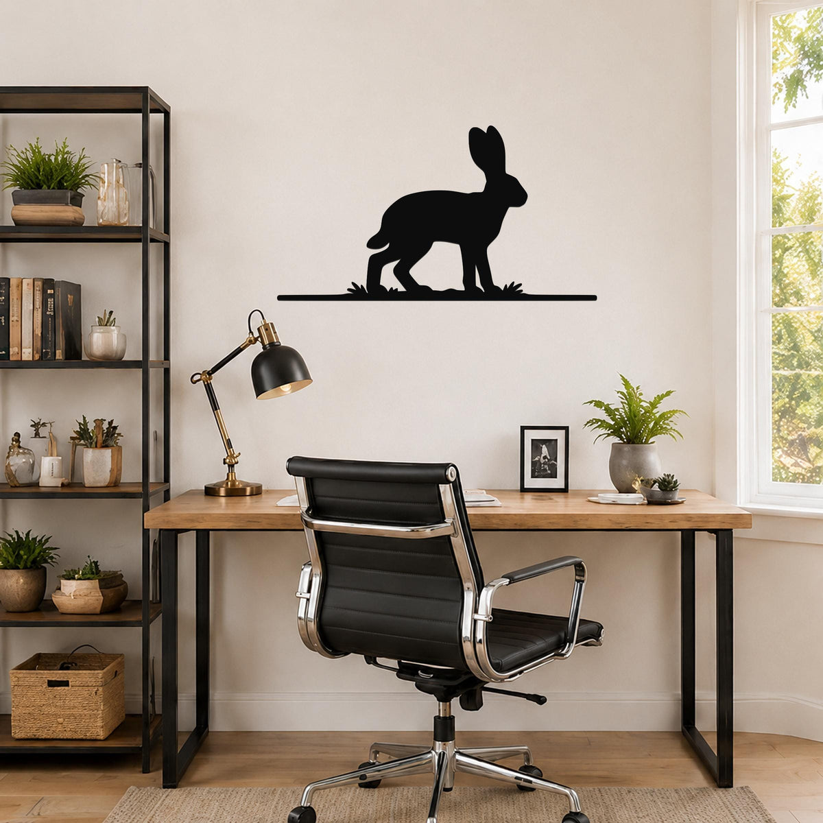 Black metal jackrabbit wall art silhouette mounted above a wooden desk in a home office.