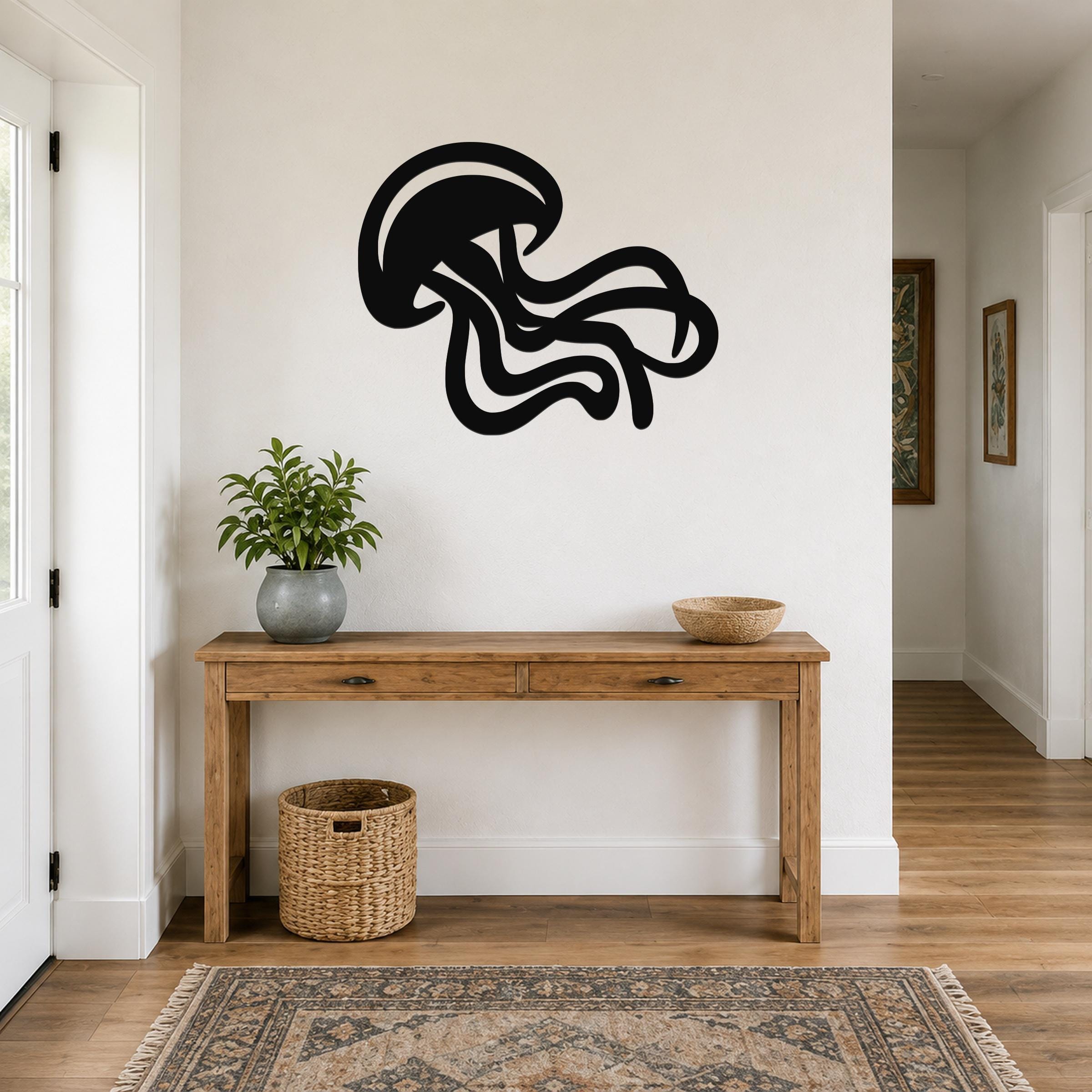 Black metal jellyfish wall art with flowing tentacle cutouts, mounted on a white wall above a wooden console table in a hallway.