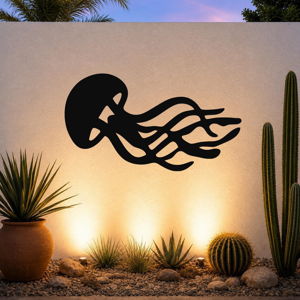 Black metal jellyfish wall art with flowing tentacle cutouts, mounted on an outdoor wall above a desert garden with cacti and warm uplighting.