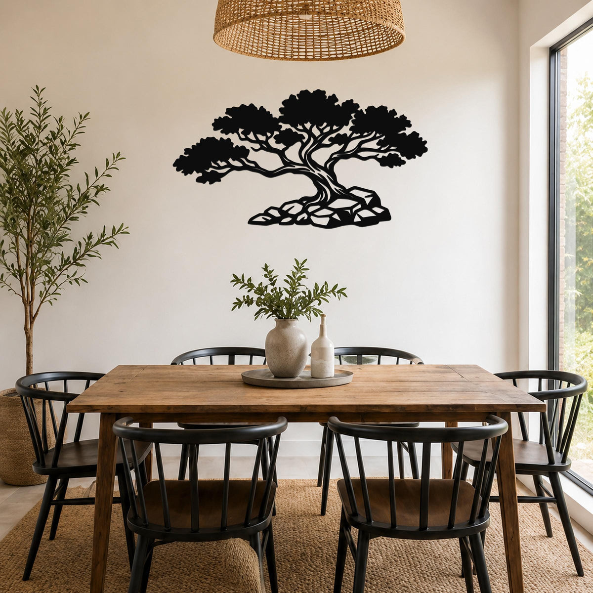 Black metal wall art of a juniper tree silhouette with detailed branches and roots, mounted on a wall above a wooden dining table in a bright room.