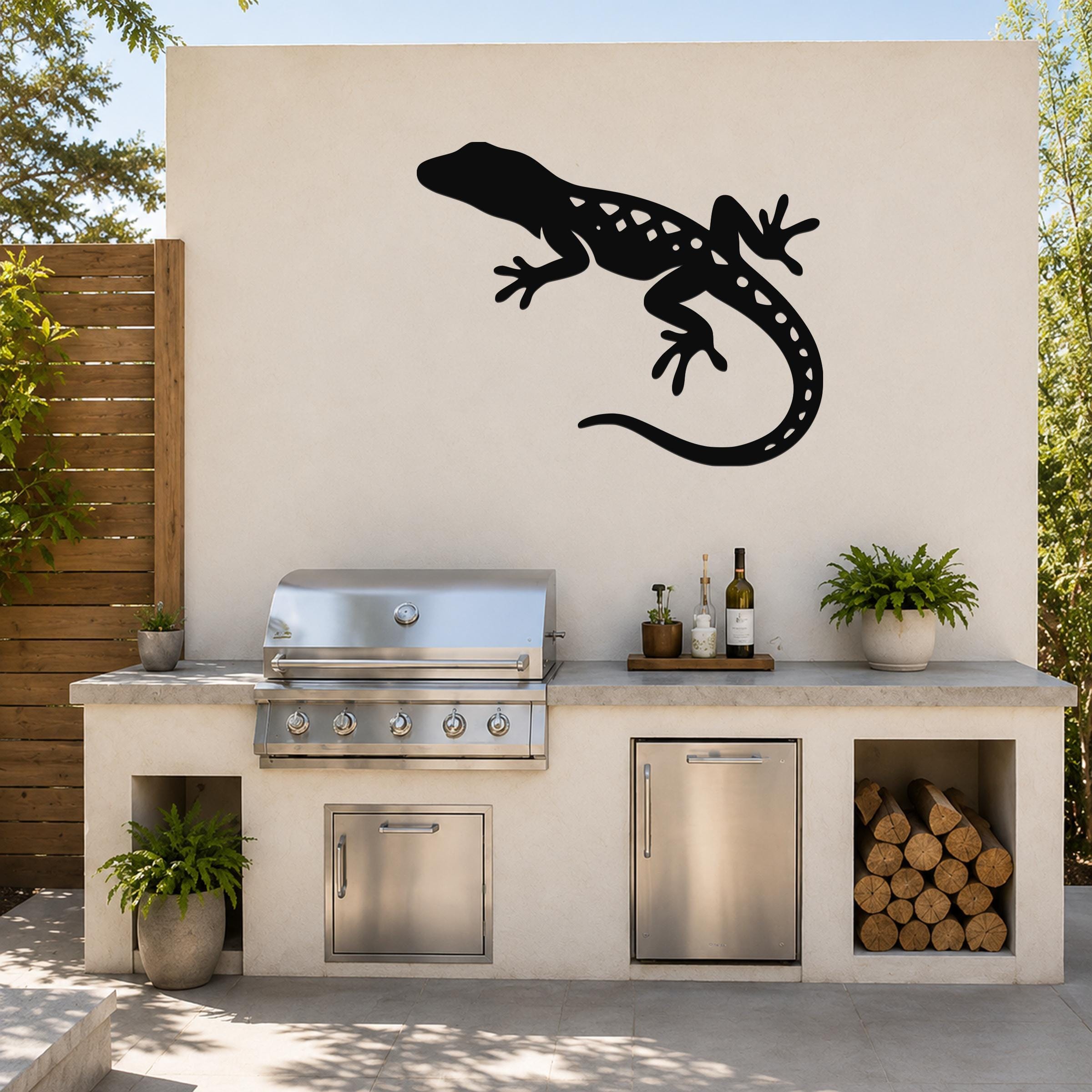 Black metal lizard wall art silhouette with internal cutout details, mounted on an outdoor patio wall above a kitchen counter.