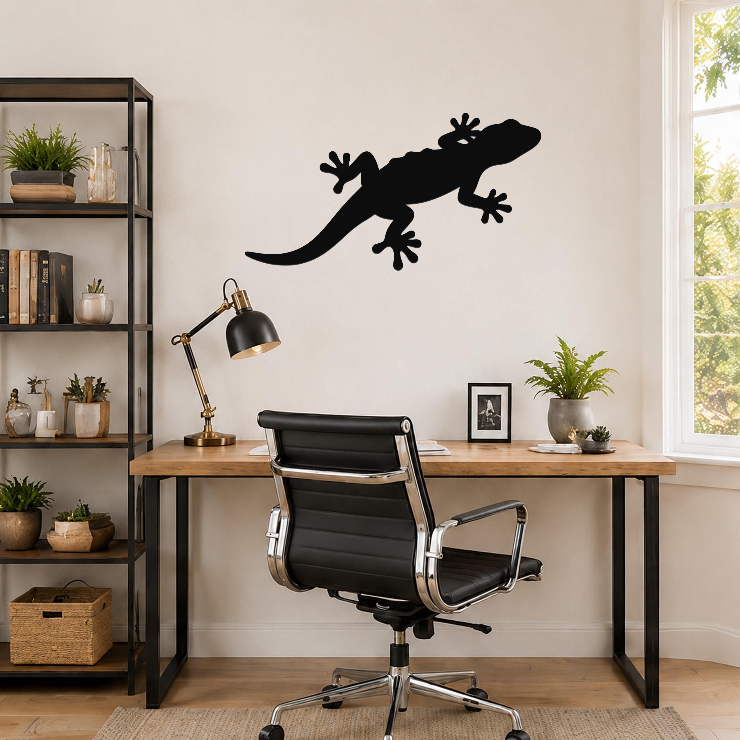 Black metal lizard wall art silhouette mounted on a wall above a wooden desk in a home office.
