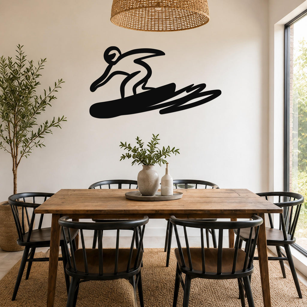 Black metal wall art silhouette of a snowboarder in motion, mounted on a wall above a wooden dining table in a bright room.