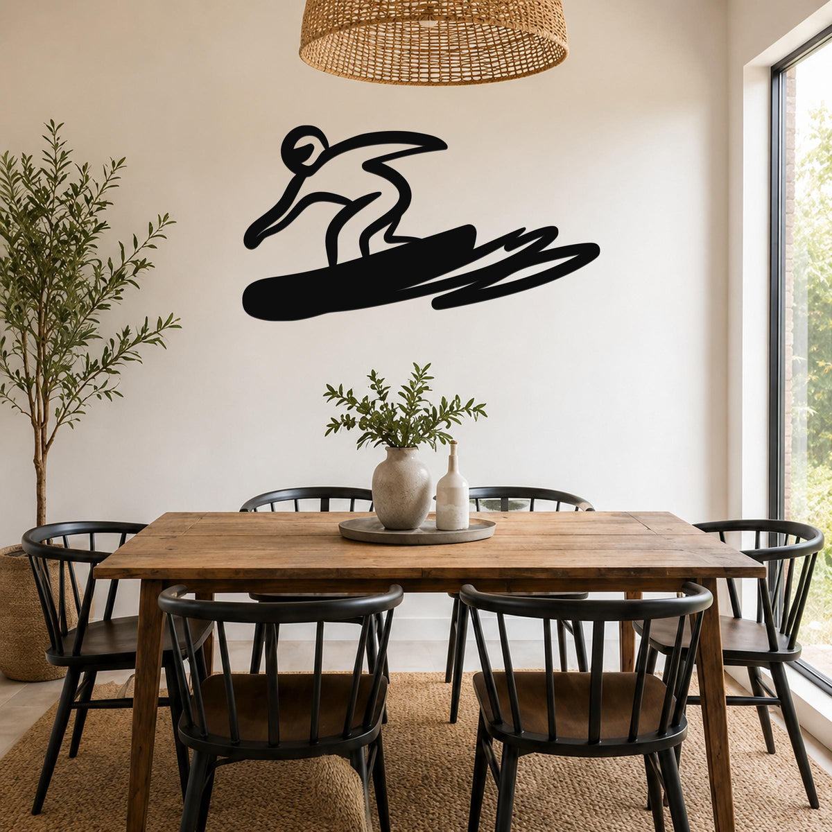 Black metal wall art silhouette of a snowboarder in motion, mounted on a wall above a wooden dining table in a bright room.