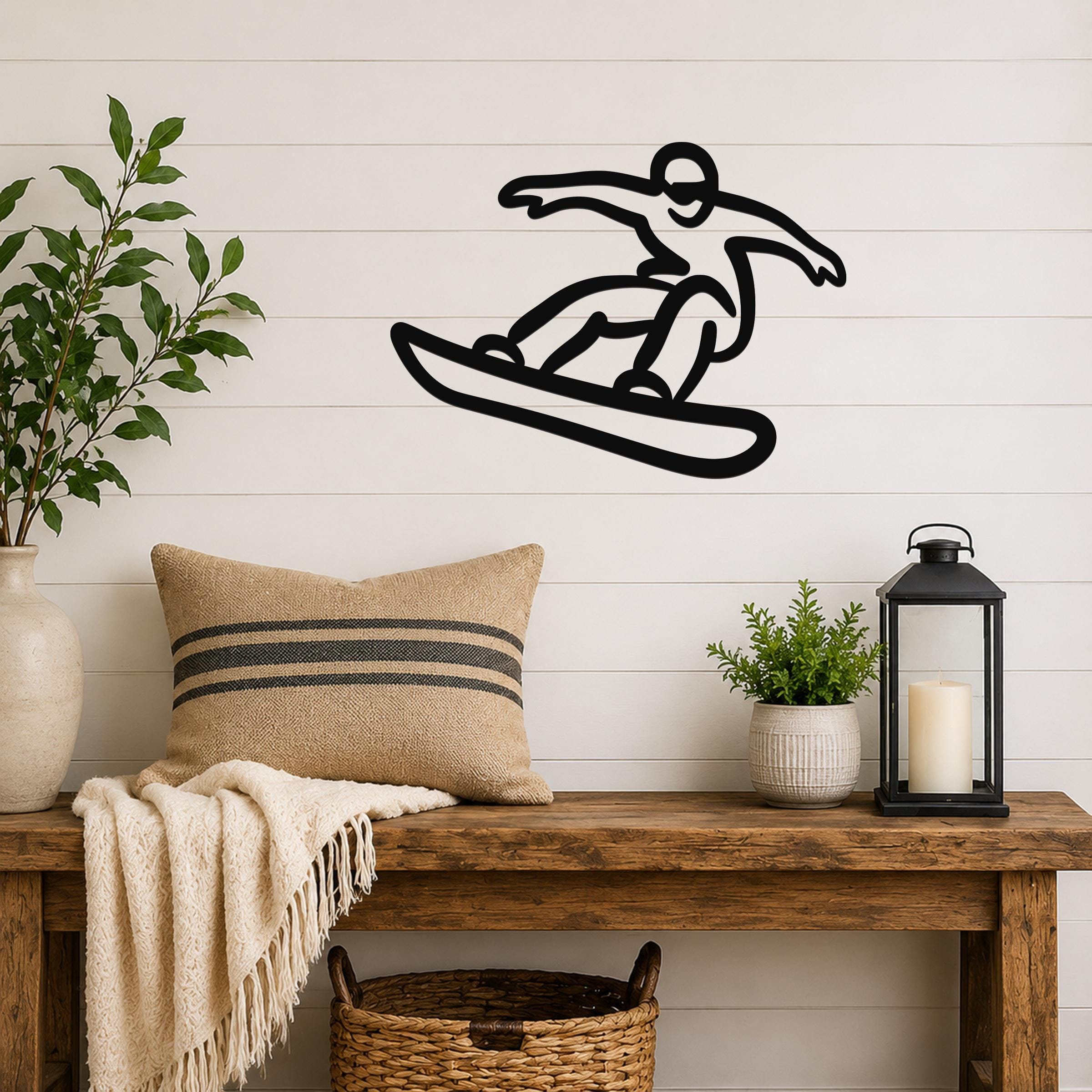 Black metal wall art silhouette of a snowboarder in motion, mounted on a white shiplap wall above a wooden bench in a living room.