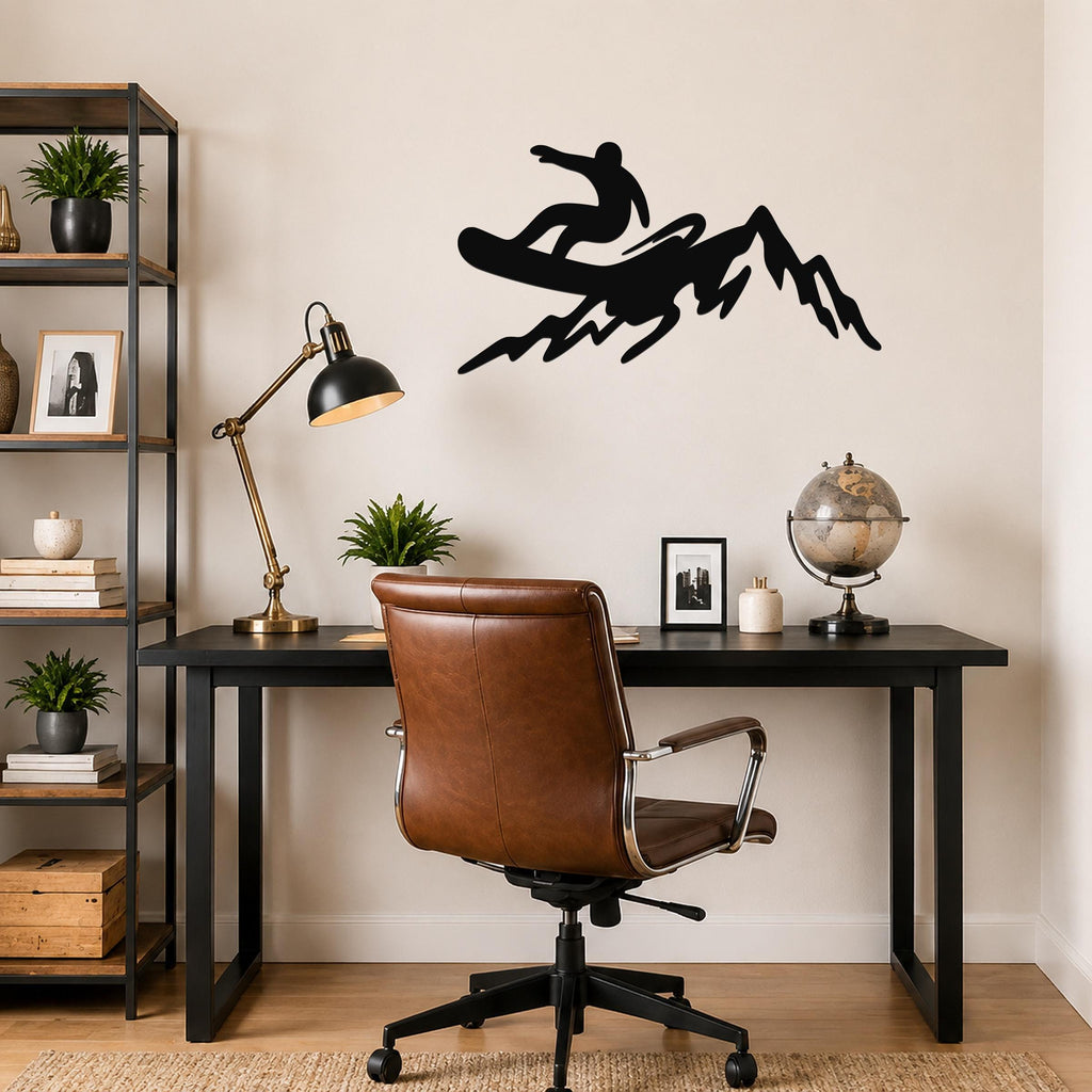 Black metal wall art silhouette of a snowboarder on a mountain, mounted above a black desk in a home office.
