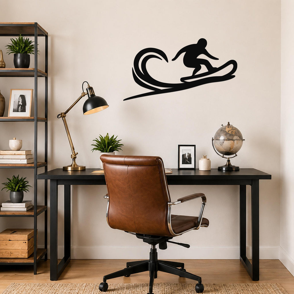 Black metal wall art silhouette of a surfer on a wave, mounted above a black desk in a home office.