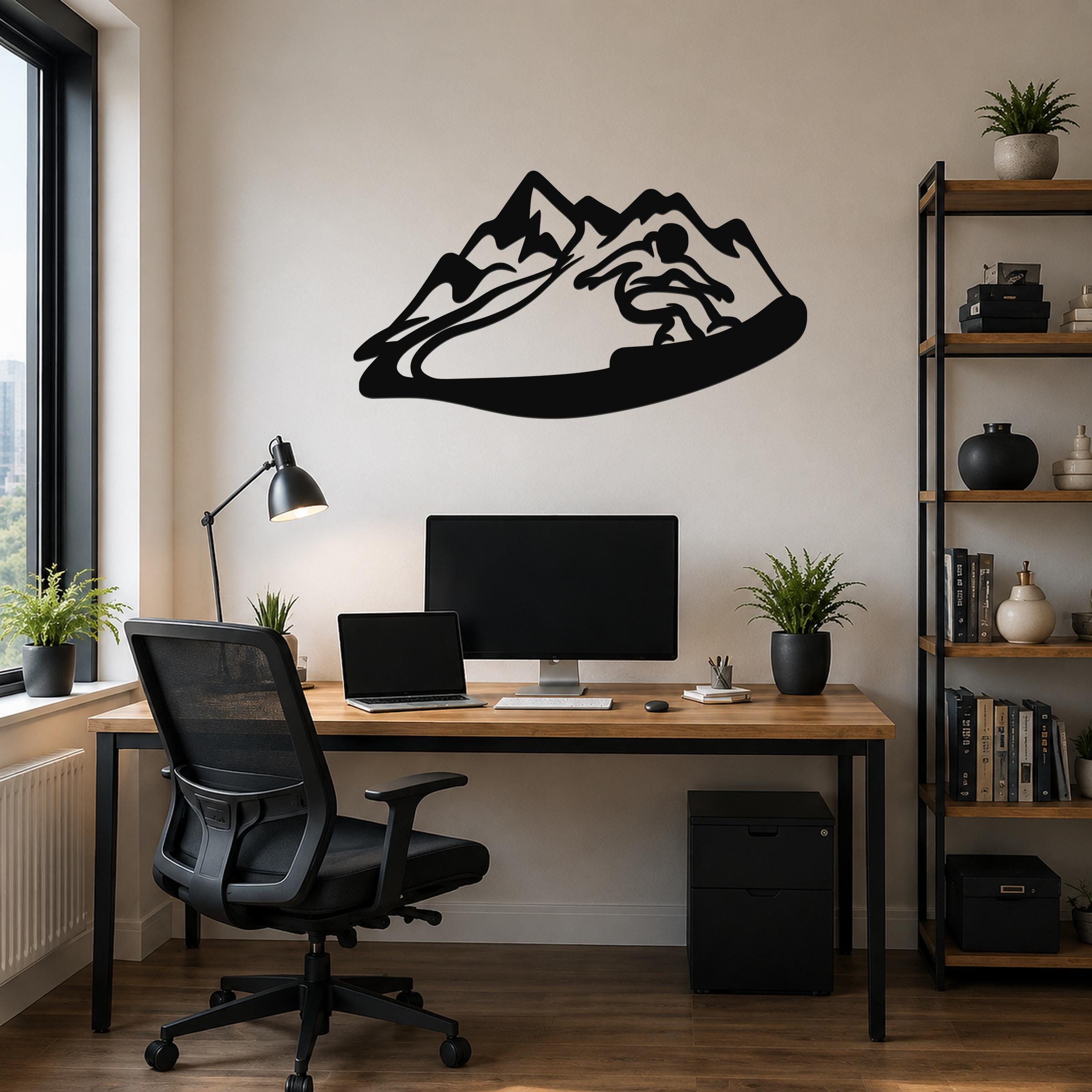 Black metal wall art with a snowboarder silhouette and mountain range, mounted above a wooden desk in a home office.