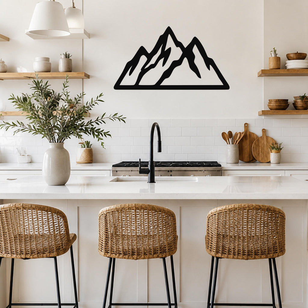 Black metal mountain silhouette wall art with layered peaks, mounted on a kitchen wall above a white countertop.