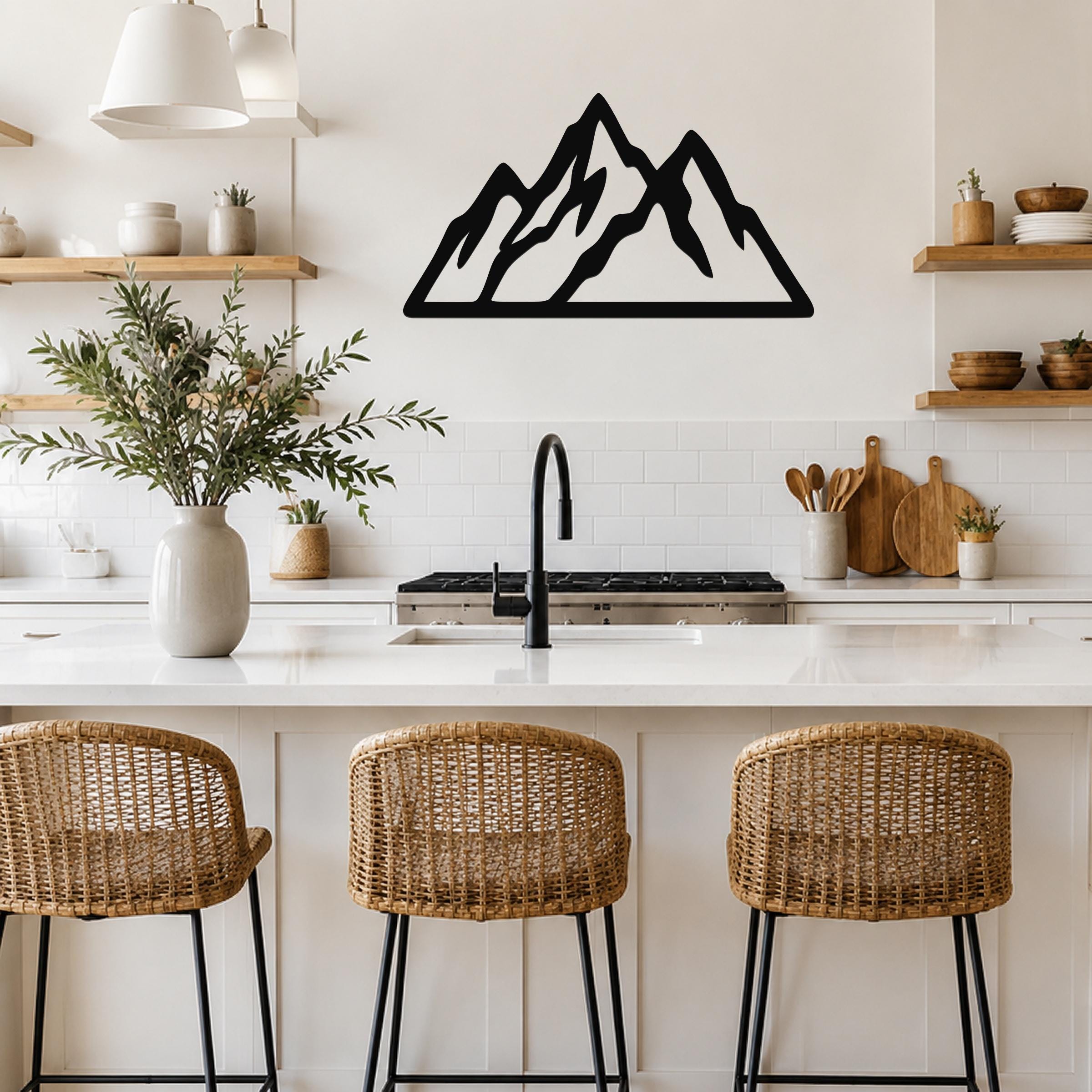 Black metal mountain silhouette wall art with layered peaks, mounted on a kitchen wall above a white countertop.