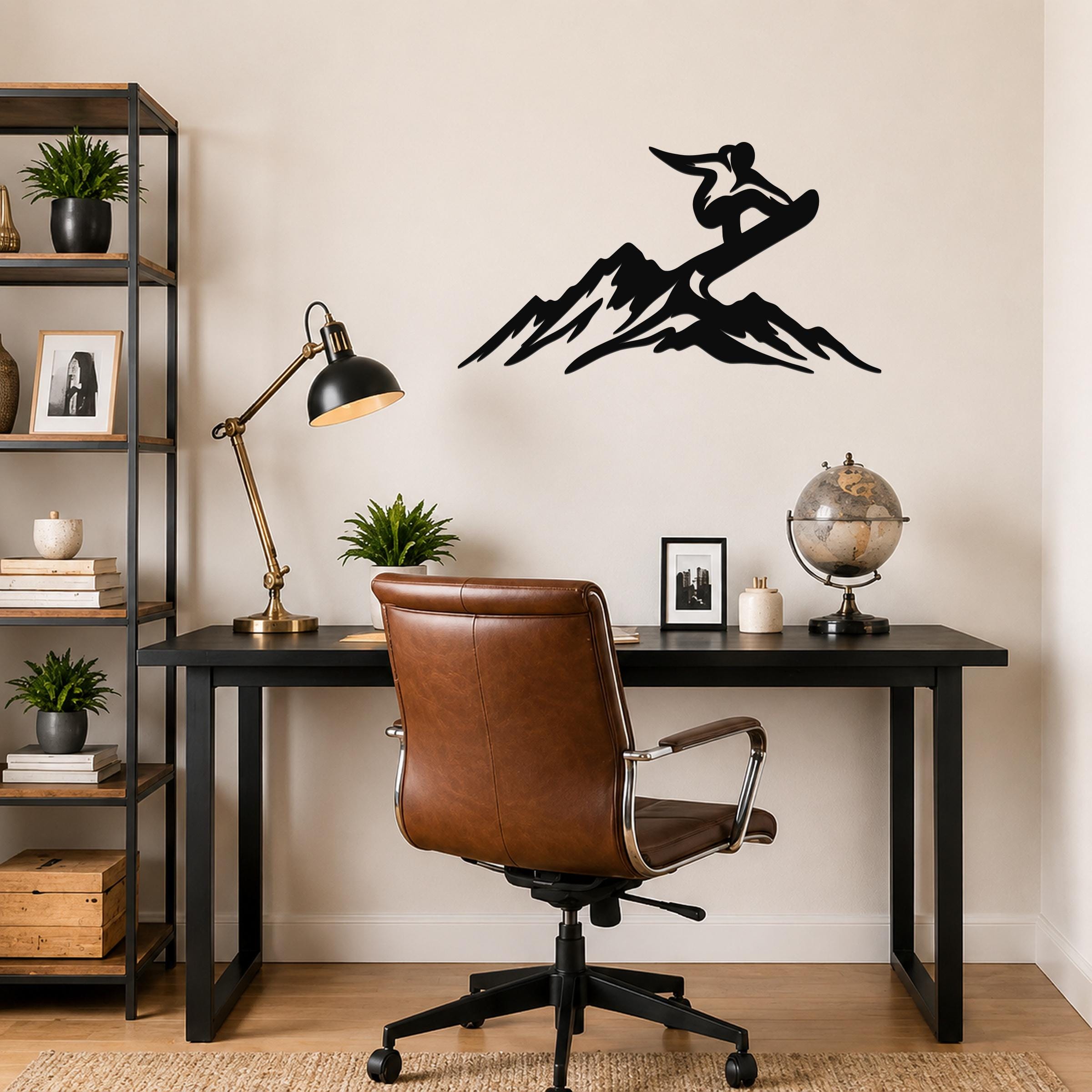 Black metal wall art silhouette of a snowboarder on a mountain, mounted above a black desk in a home office.
