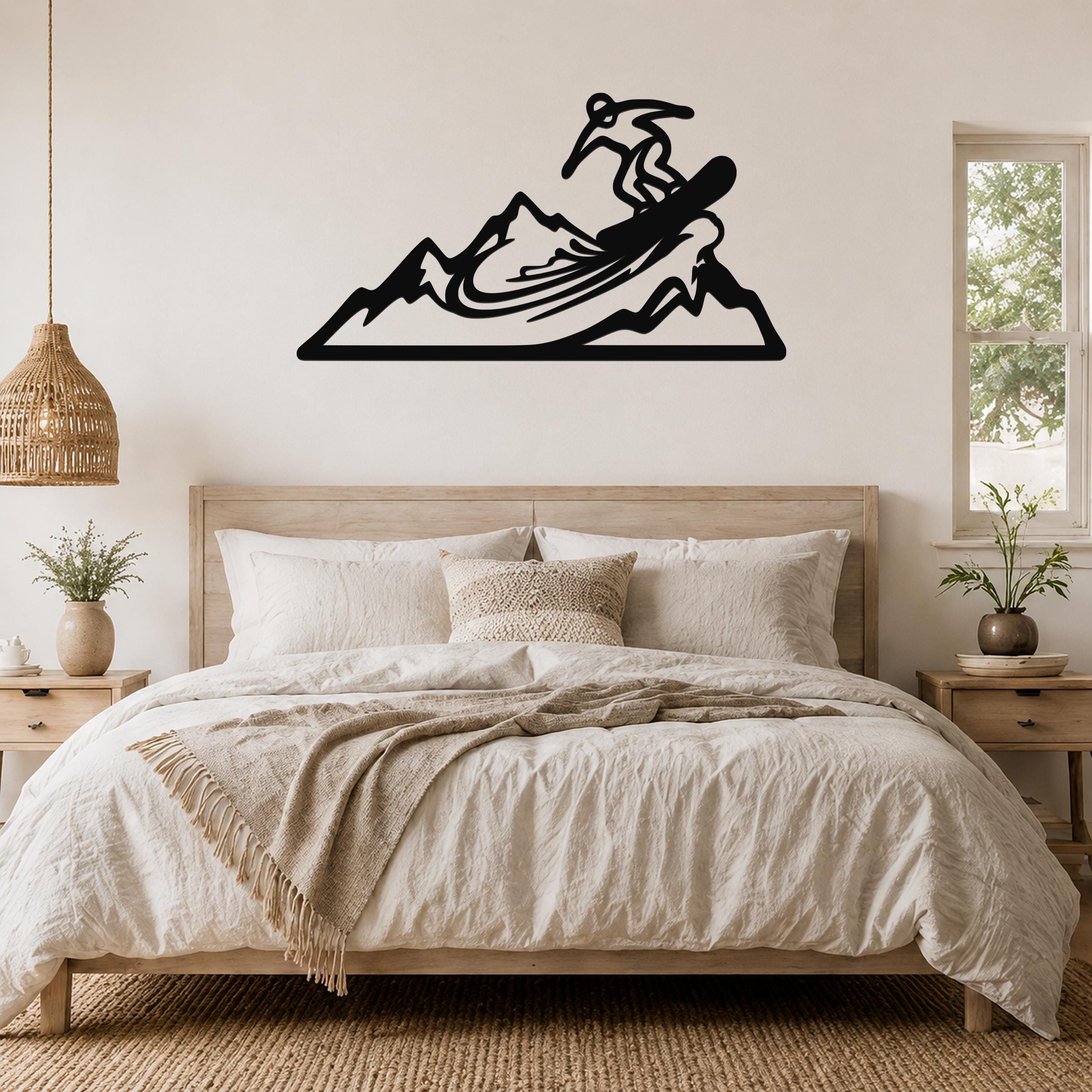 Black metal wall art cutout of a snowboarder on a mountain, mounted above a bed in a bedroom.