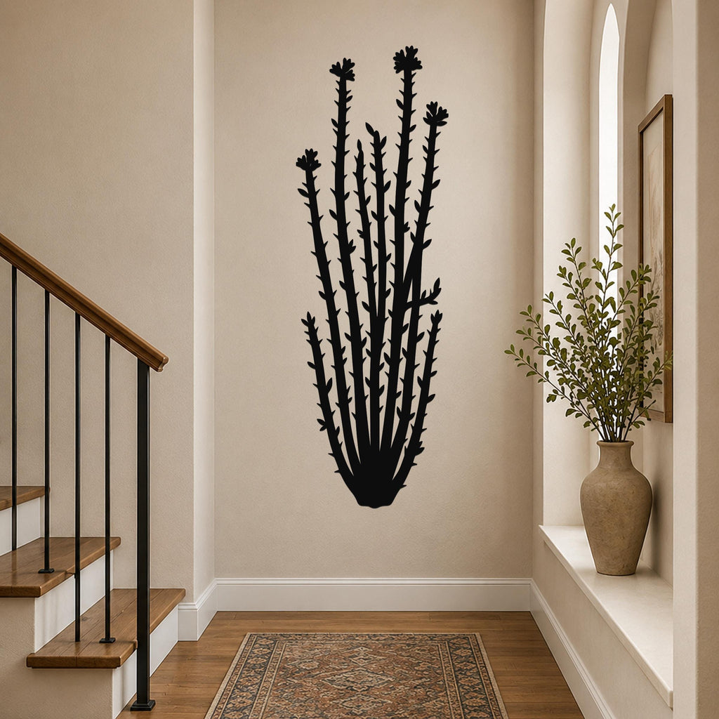 Black metal ocotillo wall art with spiny stems and flower cutouts, mounted on a hallway wall above a patterned rug.