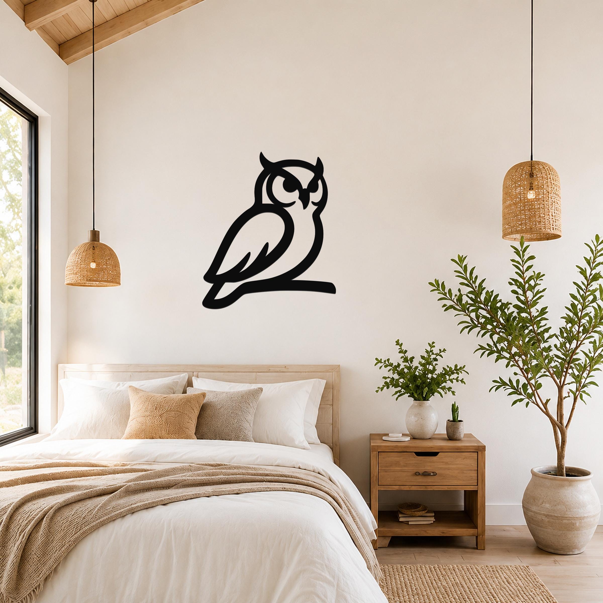 Black metal owl wall art in a silhouette style, mounted on a bedroom wall above a bed between two woven pendant lights.