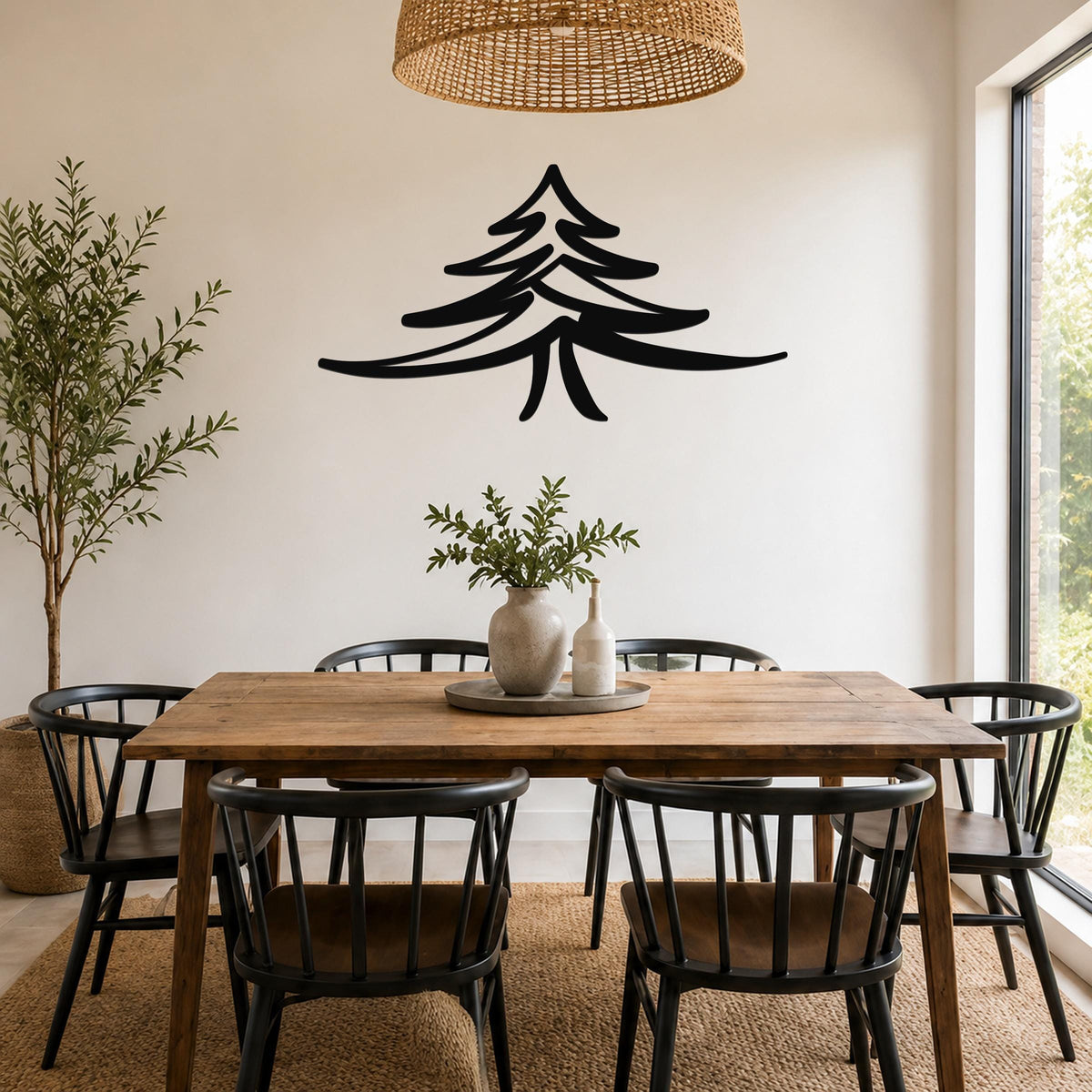 Black metal pine tree wall art silhouette mounted on a white wall above a wooden dining table in a bright, modern dining room.