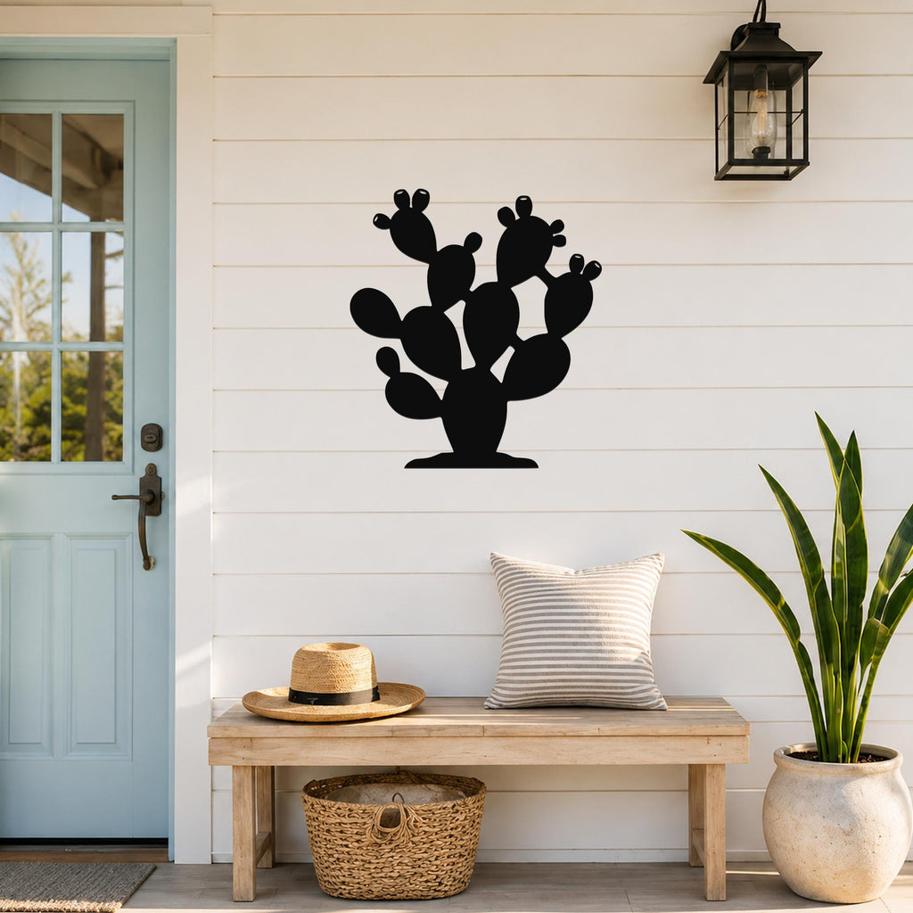 Black metal prickly pear cactus wall art with multiple pads and cutout details, mounted on a white shiplap wall above a wooden bench in a porch entryway.