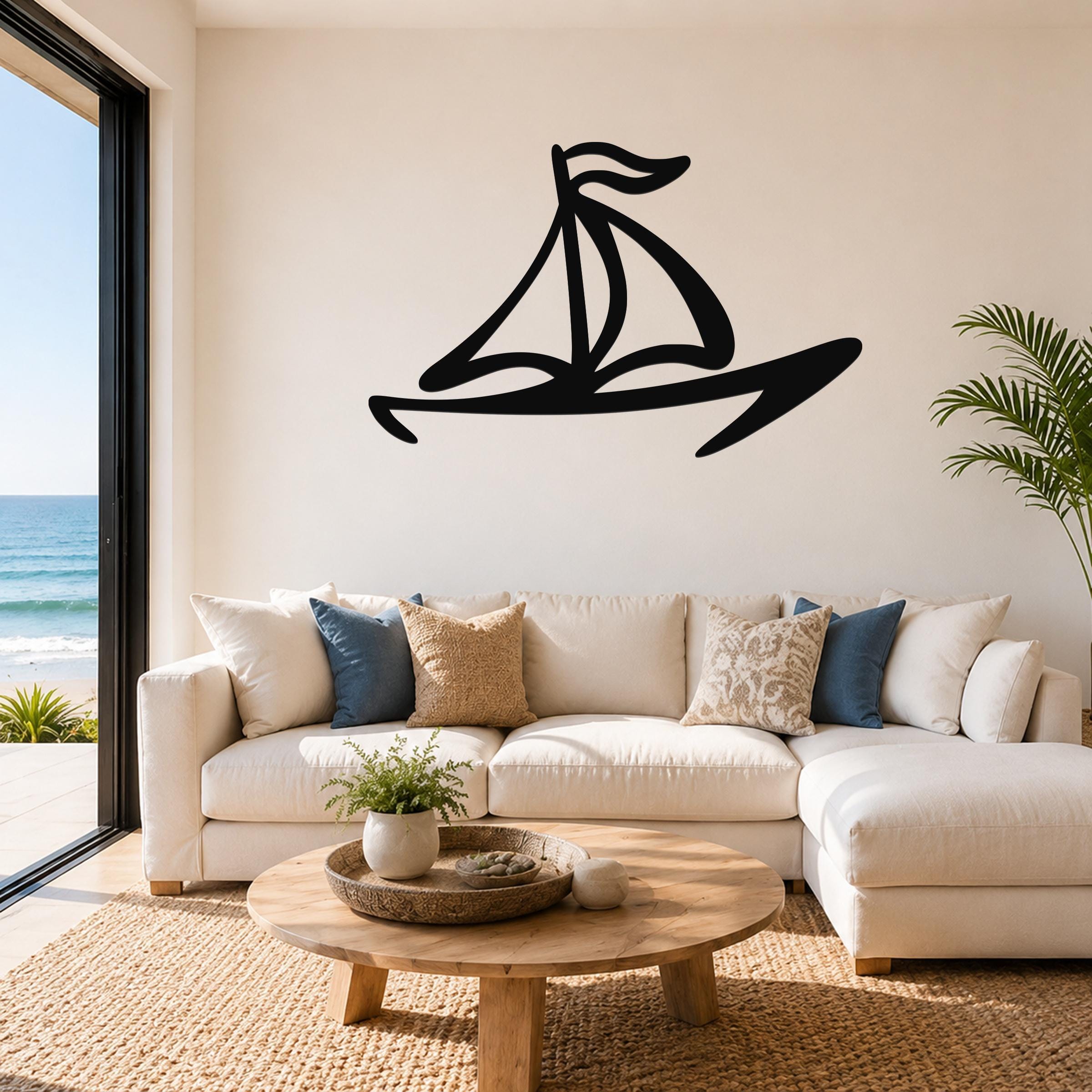 Black metal sailboat wall art with bold silhouette lines, mounted above a white sofa in a coastal living room.