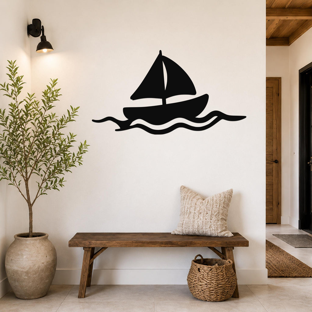 Black metal sailboat wall art with wave cutouts, mounted on a white wall above a wooden bench in a coastal entryway.