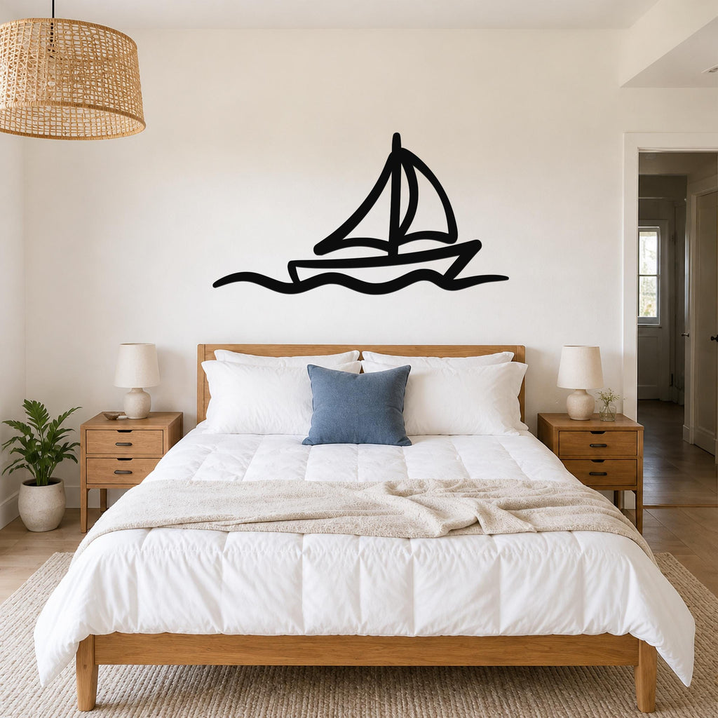Black metal sailboat wall art with wavy line cutout, mounted above a bed in a bedroom.
