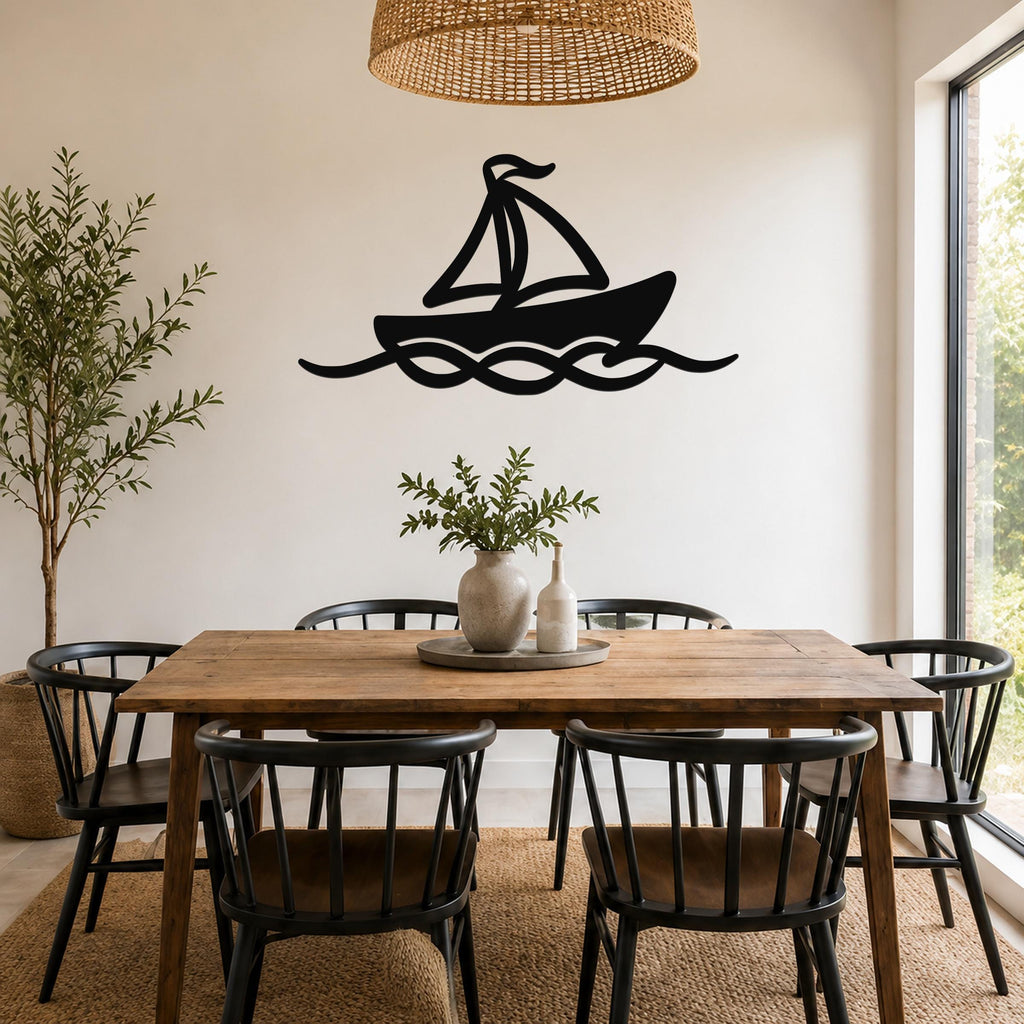 Black metal sailboat wall art with wave cutouts, mounted on a dining room wall above a wooden table.