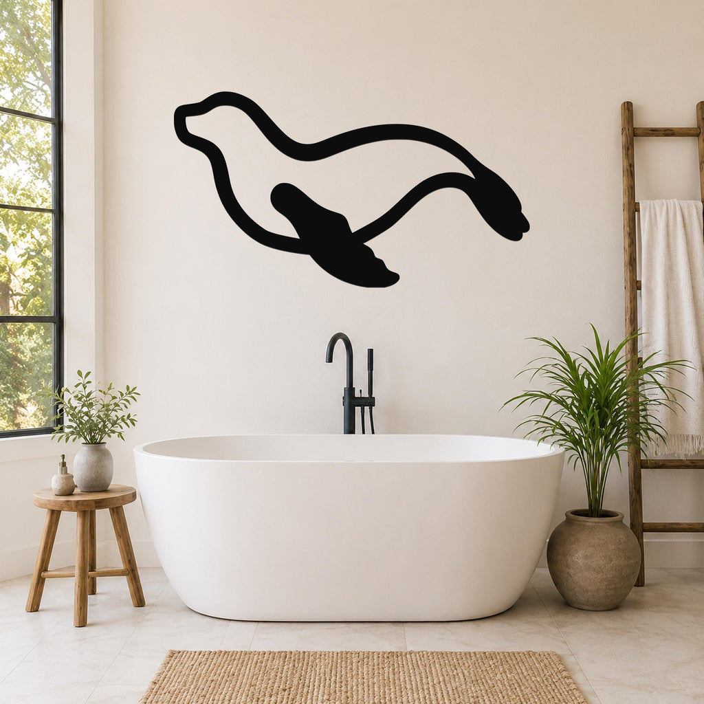 Black metal sea lion wall art with flowing motion lines, mounted on a bathroom wall above a freestanding tub.