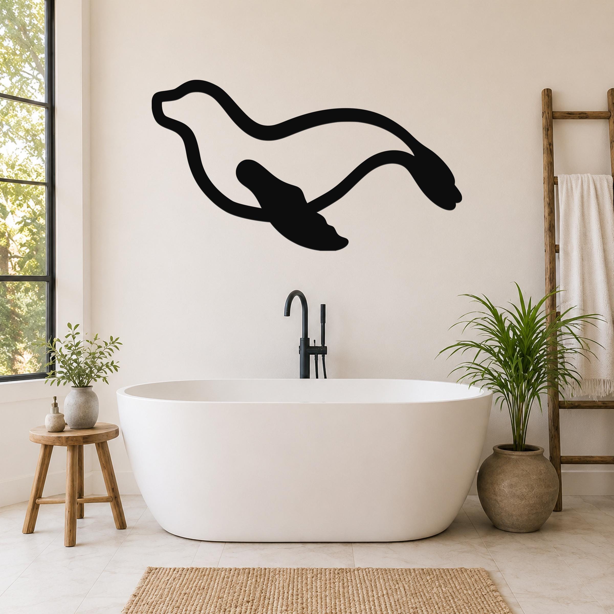 Black metal sea lion wall art with flowing motion lines, mounted on a bathroom wall above a freestanding tub.
