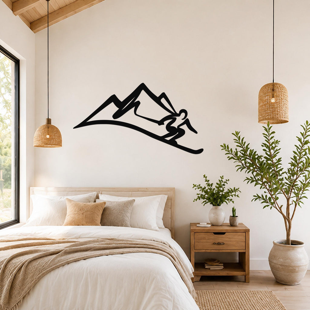 Black metal wall art silhouette of a skier in motion on a mountain slope, mounted above a bed in a bedroom with wooden furniture and woven pendant lights.