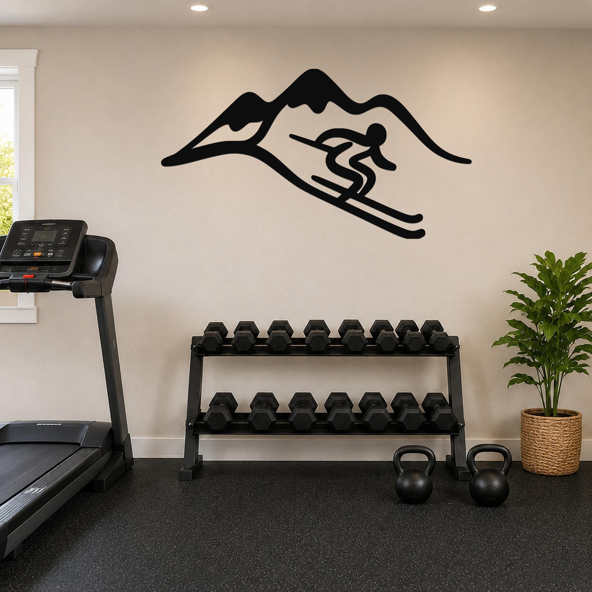 Black metal wall art featuring a skier silhouette in motion above a mountain range, mounted on a light-colored wall above a dumbbell rack in a home gym.